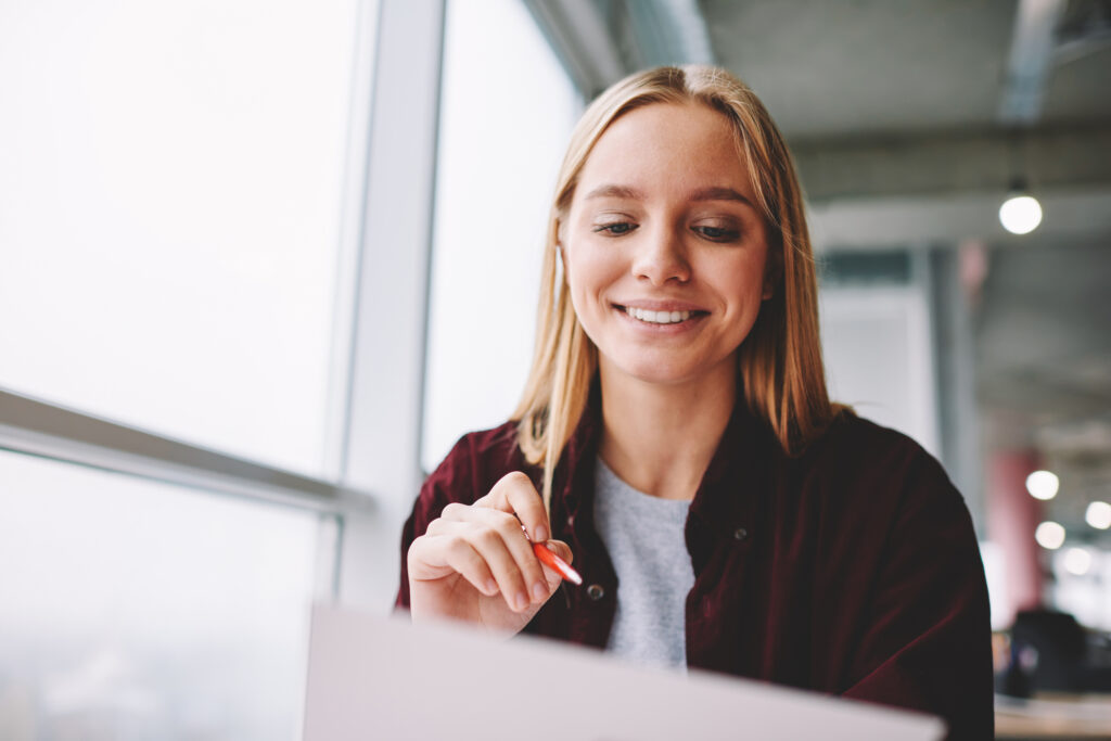 Positive blonde woman fill in information in questionnaire making application for hire on vacancy, smiling female students satisfied with know answers for test completing writing with pen indoors